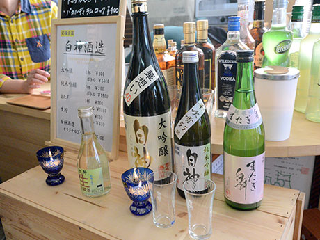 O presidente da Shirakami Sake Brewery vende saquê que sobreviveu ao incêndio em um evento local