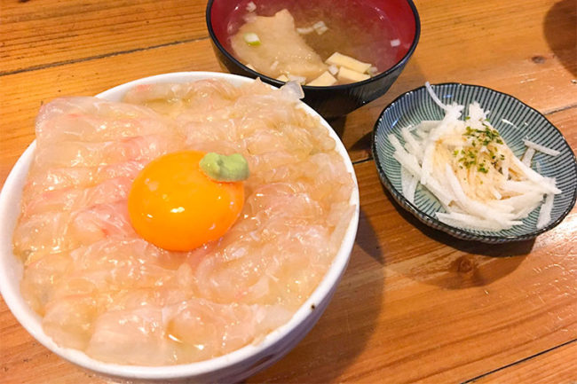 Um brilhante tigela de arroz em conserva de peixe chato que atrai a atenção de uma pequena sala de jantar na cidade portuária de Aomori
