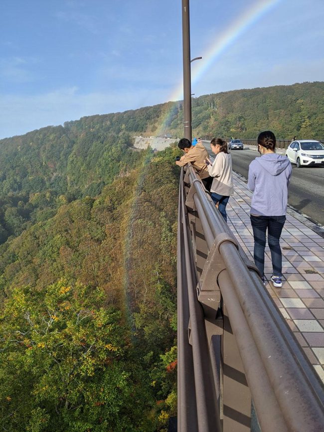 一条彩虹挂在青森/白樱桥的上方，一直到彩虹桥的底部