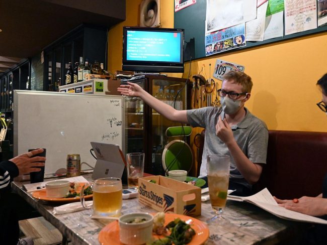 Американцы берут уроки разговорного английского в баре в Хиросаки в целях культурного обмена.